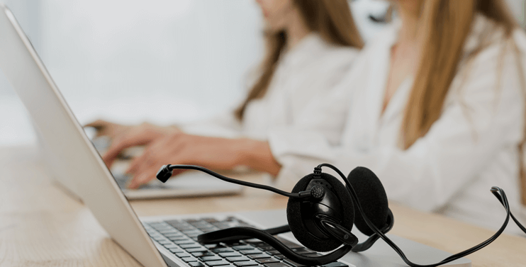 Foto representativa de um departamento de suporte com mulheres usando notebooks e headset